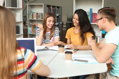 Young people discussing group project at table in library