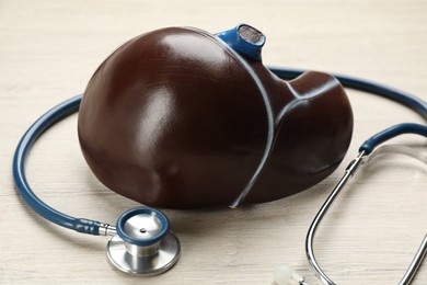 Photo of Stethoscope and liver model on white wooden table