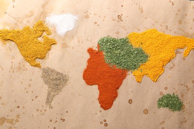 Photo of World map of different spices on old paper, flat lay