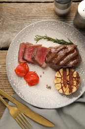 Photo of Delicious grilled beef steak served with spices and tomatoes on wooden table, top view