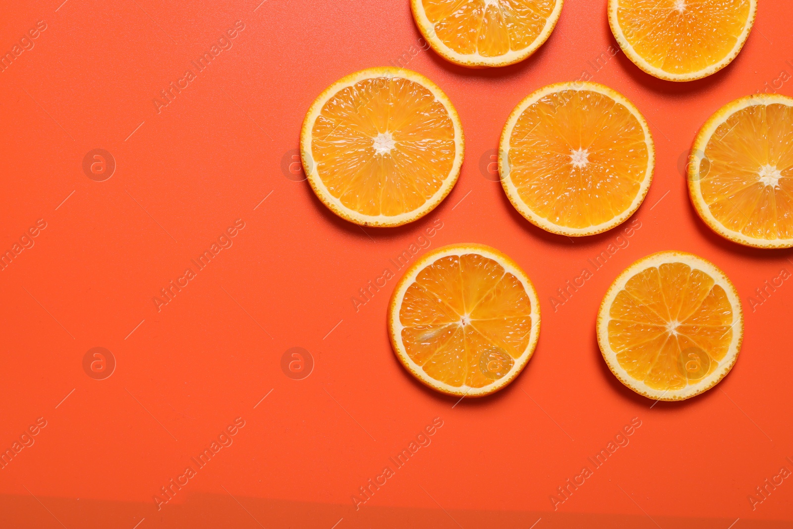 Photo of Slices of juicy orange on terracotta background, flat lay. Space for text