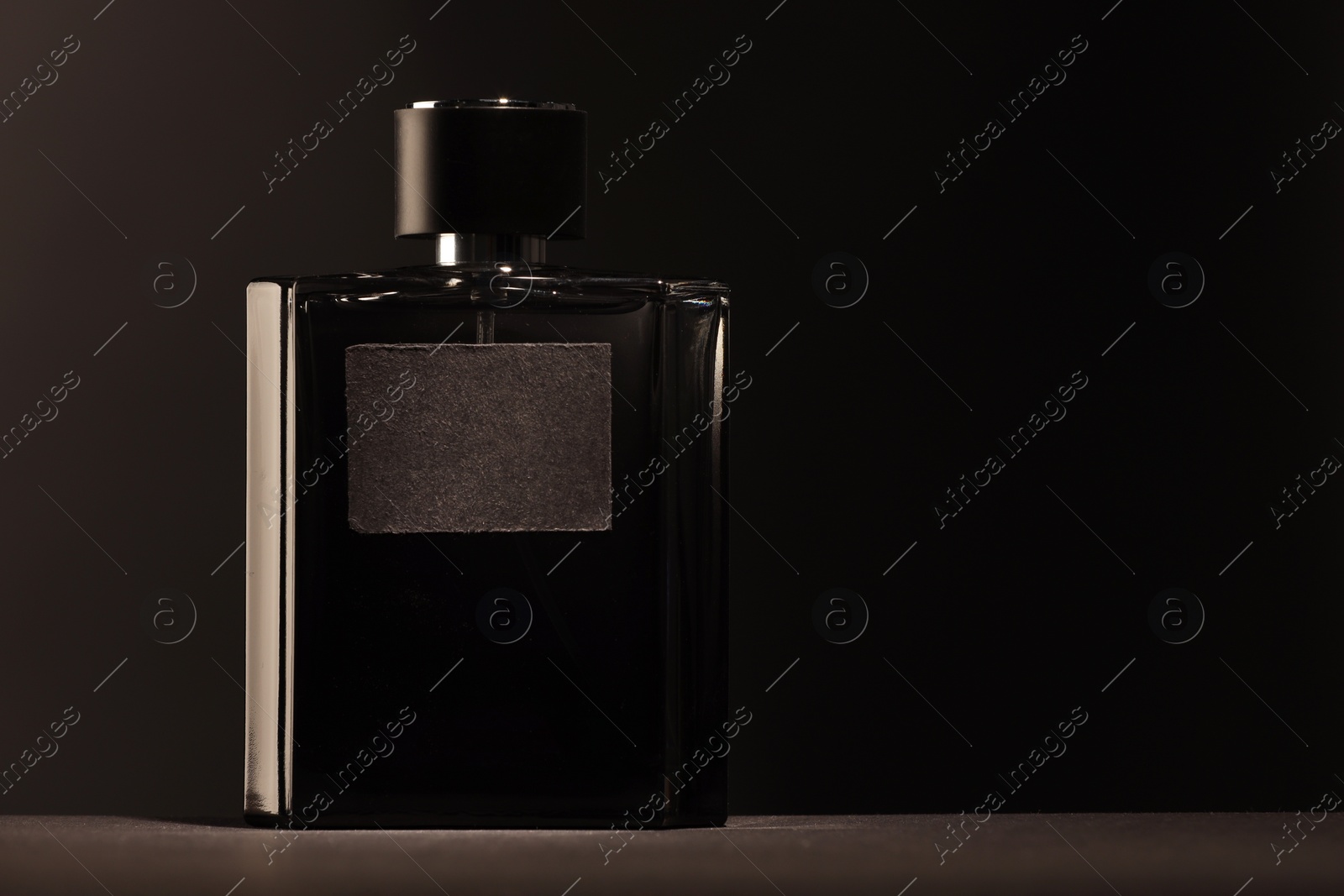 Photo of Luxury men`s perfume in bottle on table against dark background, space for text