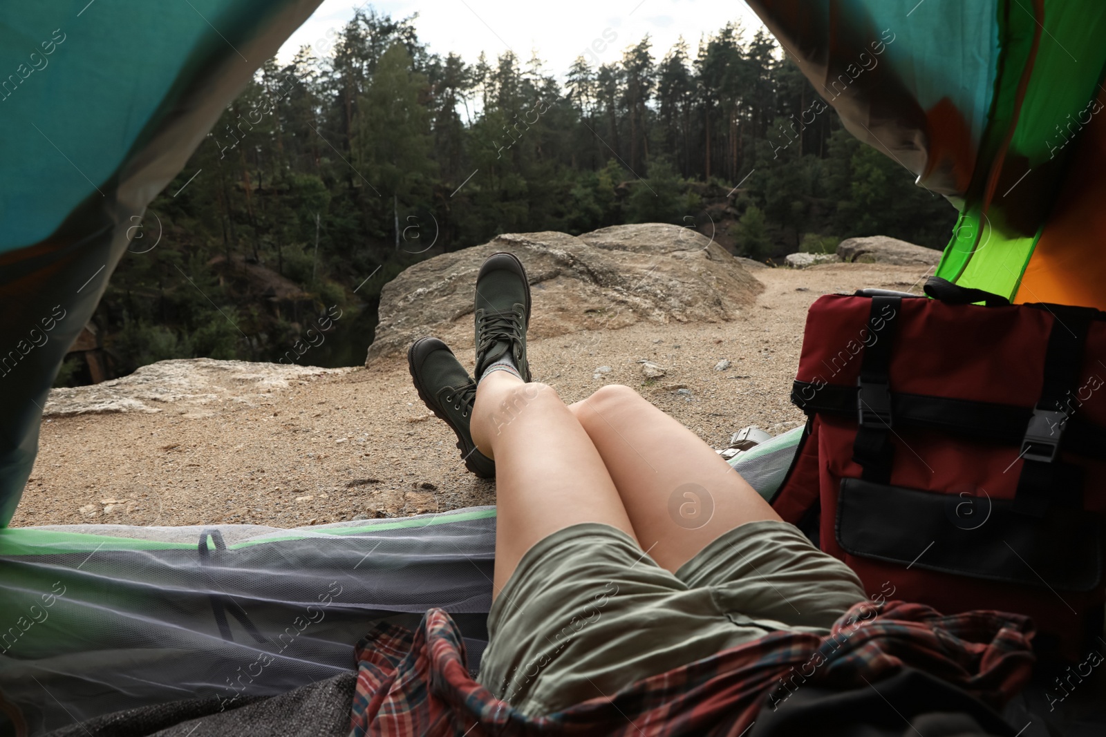 Photo of Young woman resting in camping tent, view from inside