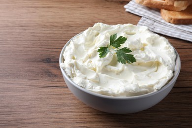 Photo of Tasty cream cheese with parsley on wooden table. Space for text