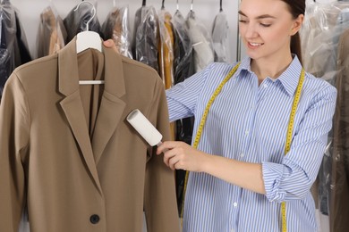 Young woman using adhesive lint roller at dry-cleaner's