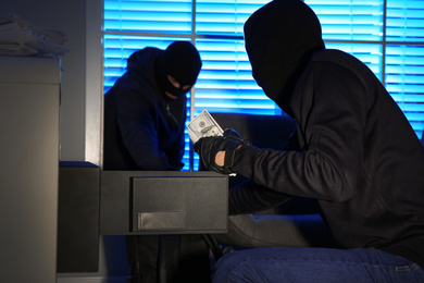 Thieves taking money out of steel safe indoors at night