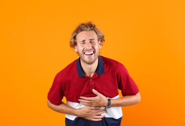 Handsome young man laughing on color background