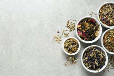 Photo of Flat lay composition with different dry teas on light grey table, space for text