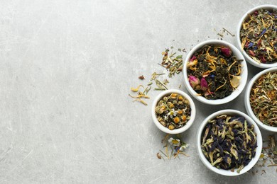 Flat lay composition with different dry teas on light grey table, space for text