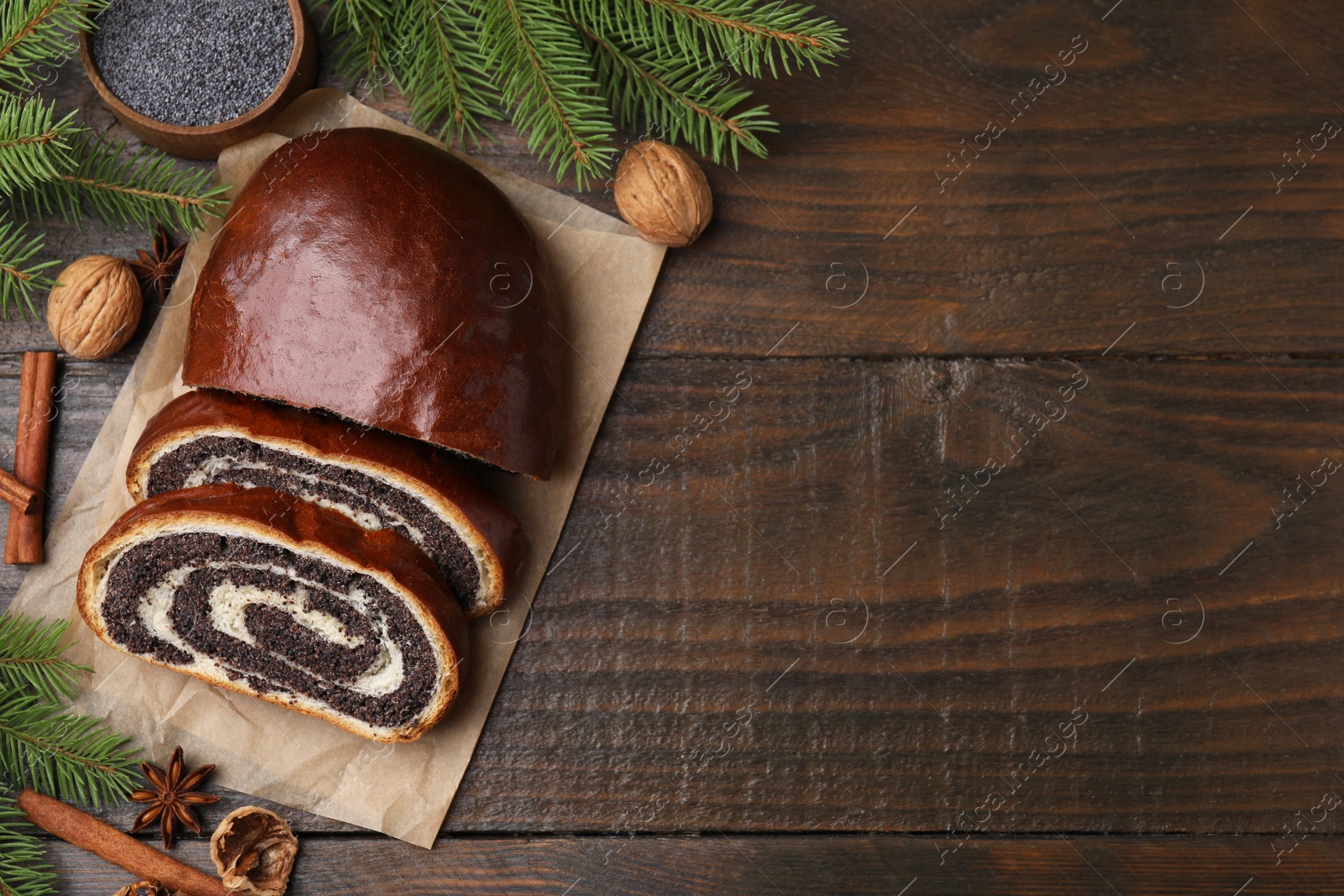 Photo of Flat lay composition with cut poppy seed roll and fir branches on wooden table with space for text. Tasty cake