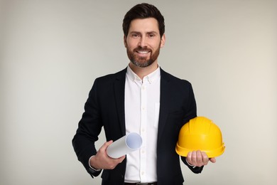 Photo of Architect with draft and hard hat on gray background