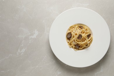 Photo of Delicious pasta with truffle slices and cheese on light grey table, top view. Space for text