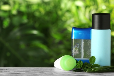 Photo of Natural deodorants with aloe and mint on wooden table against blurred green background. Space for text