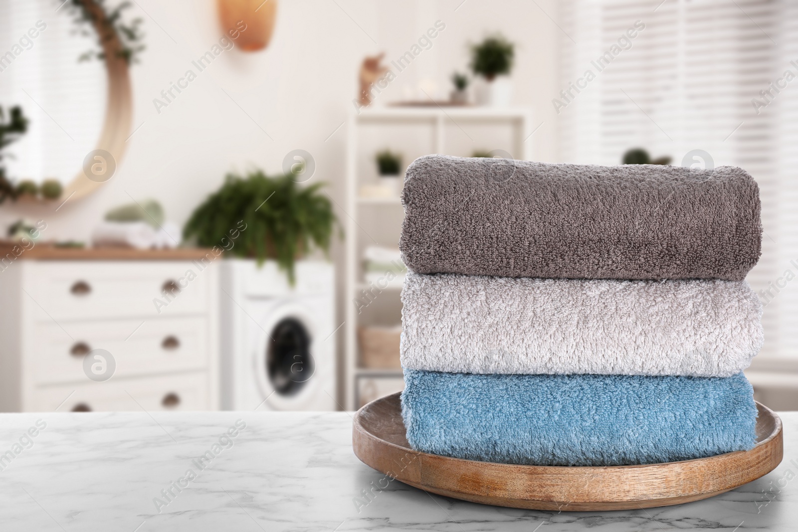 Image of Tray with clean soft towels on white marble table in bathroom. Space for text