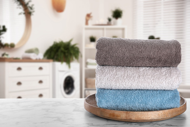 Tray with clean soft towels on white marble table in bathroom. Space for text