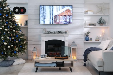 Stylish living room interior with modern TV, fireplace and Christmas tree