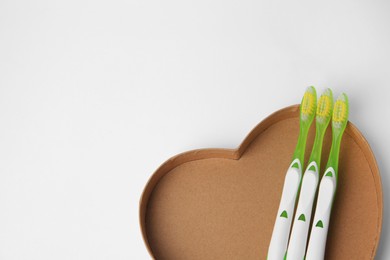 Photo of Light green toothbrushes on white background, above view. Space for text