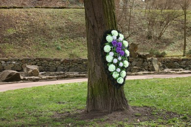 Funeral wreath of flowers on tree outdoors