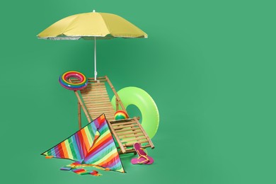 Photo of Deck chair, kite and beach accessories on green background, space for text