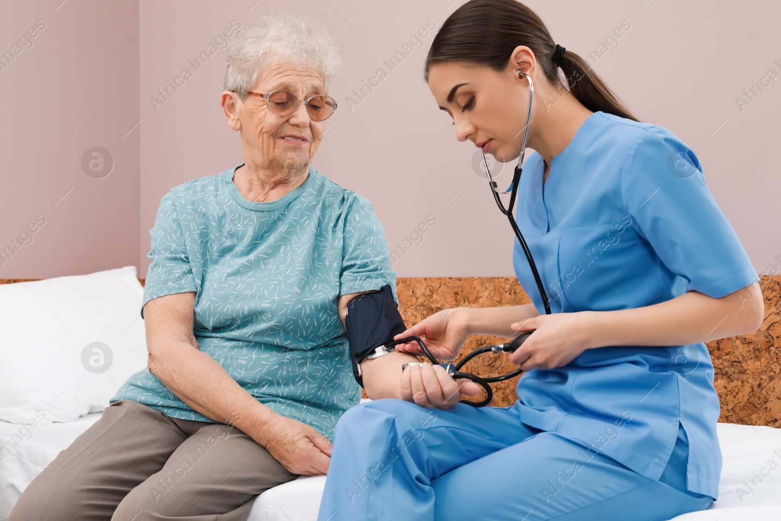 Photo of Nurse measuring senior woman's blood pressure in hospital ward. Medical assisting