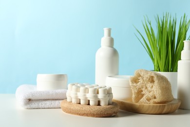 Photo of Different bath accessories and houseplant on white table against light blue background. Space for text