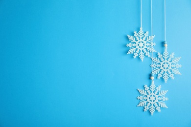 Beautiful decorative snowflakes hanging on light blue background, space for text