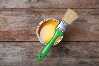 Paint can and brush on wooden background, top view