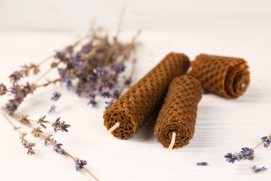 Stylish elegant beeswax candles and lavender on white wooden table