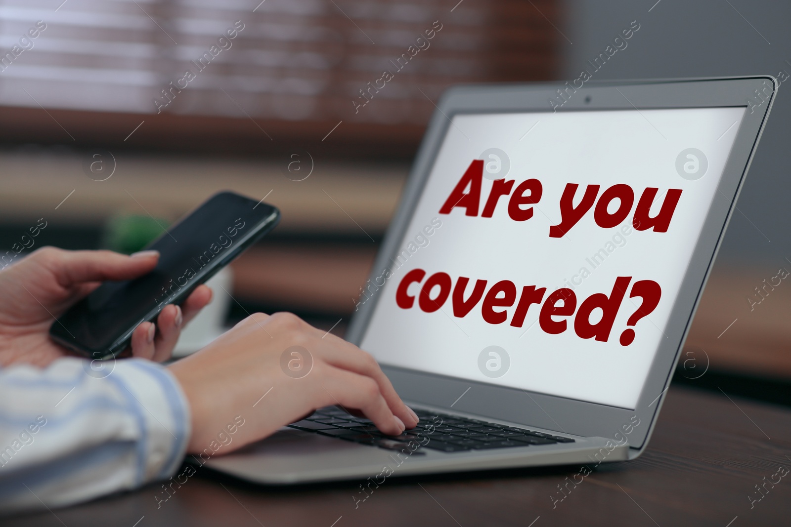 Image of Woman and laptop with text ARE YOU COVERED? on screen indoors, closeup. Insurance concept