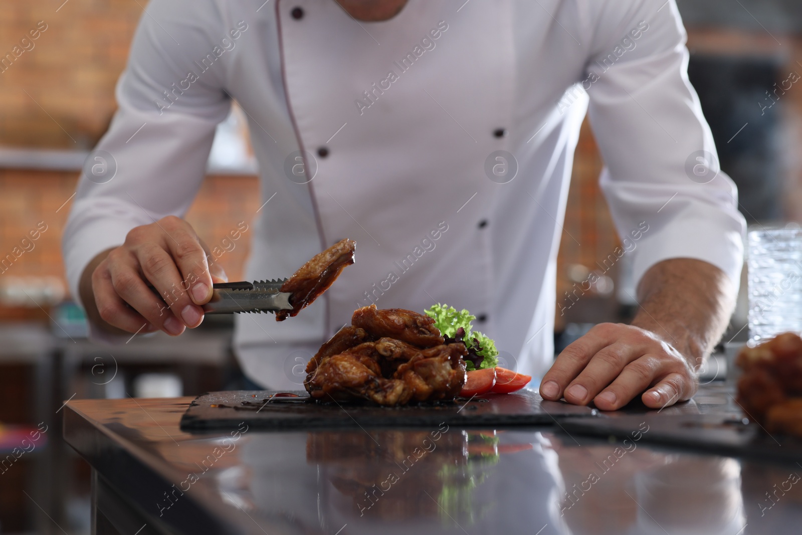 Photo of Professional chef with delicious fried chicken wings in restaurant kitchen, closeup