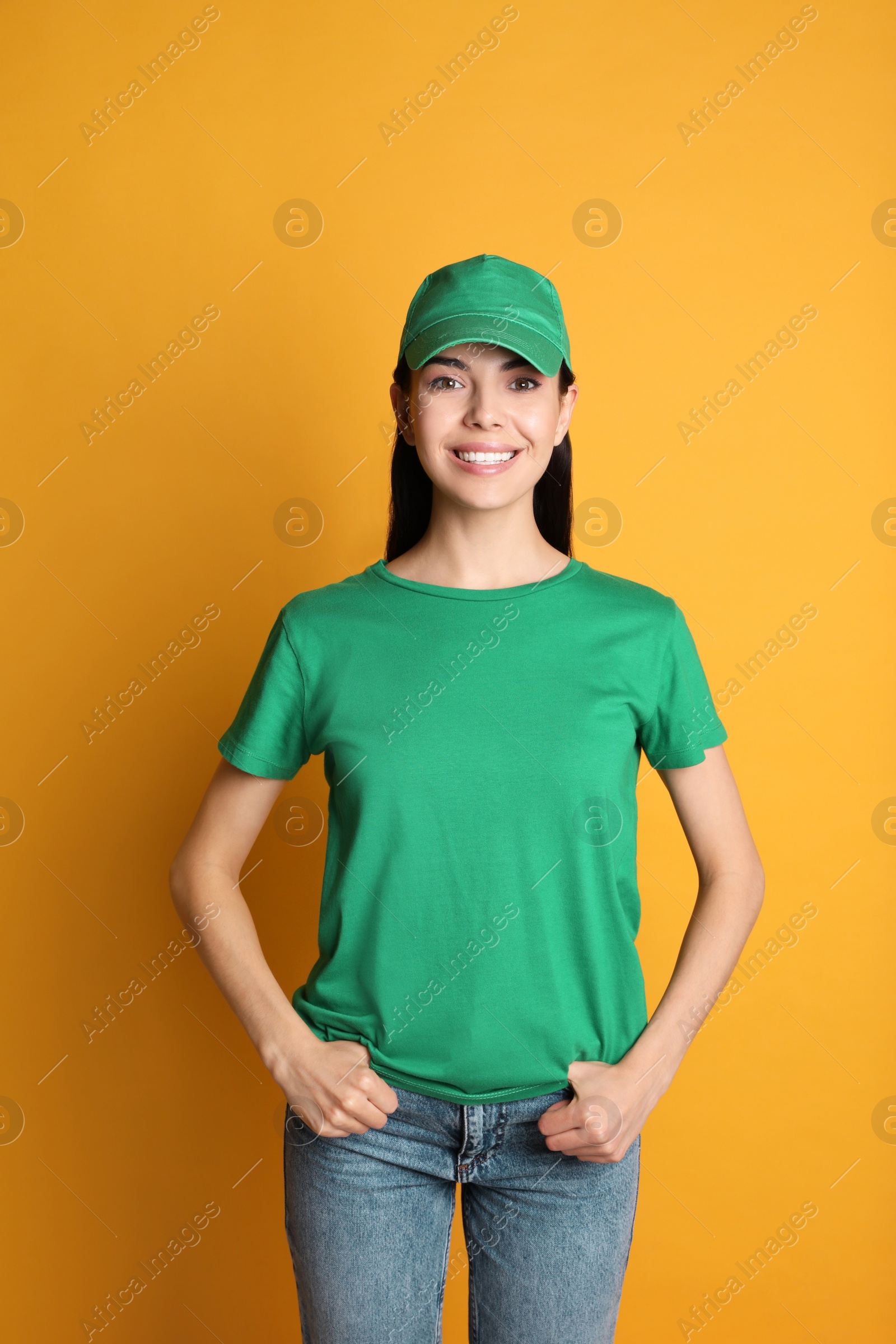 Photo of Young happy woman in green cap and tshirt on yellow background. Mockup for design