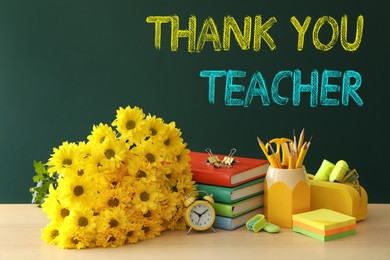 Set of stationery and flowers on wooden table near chalkboard with phrase Thank You Teacher