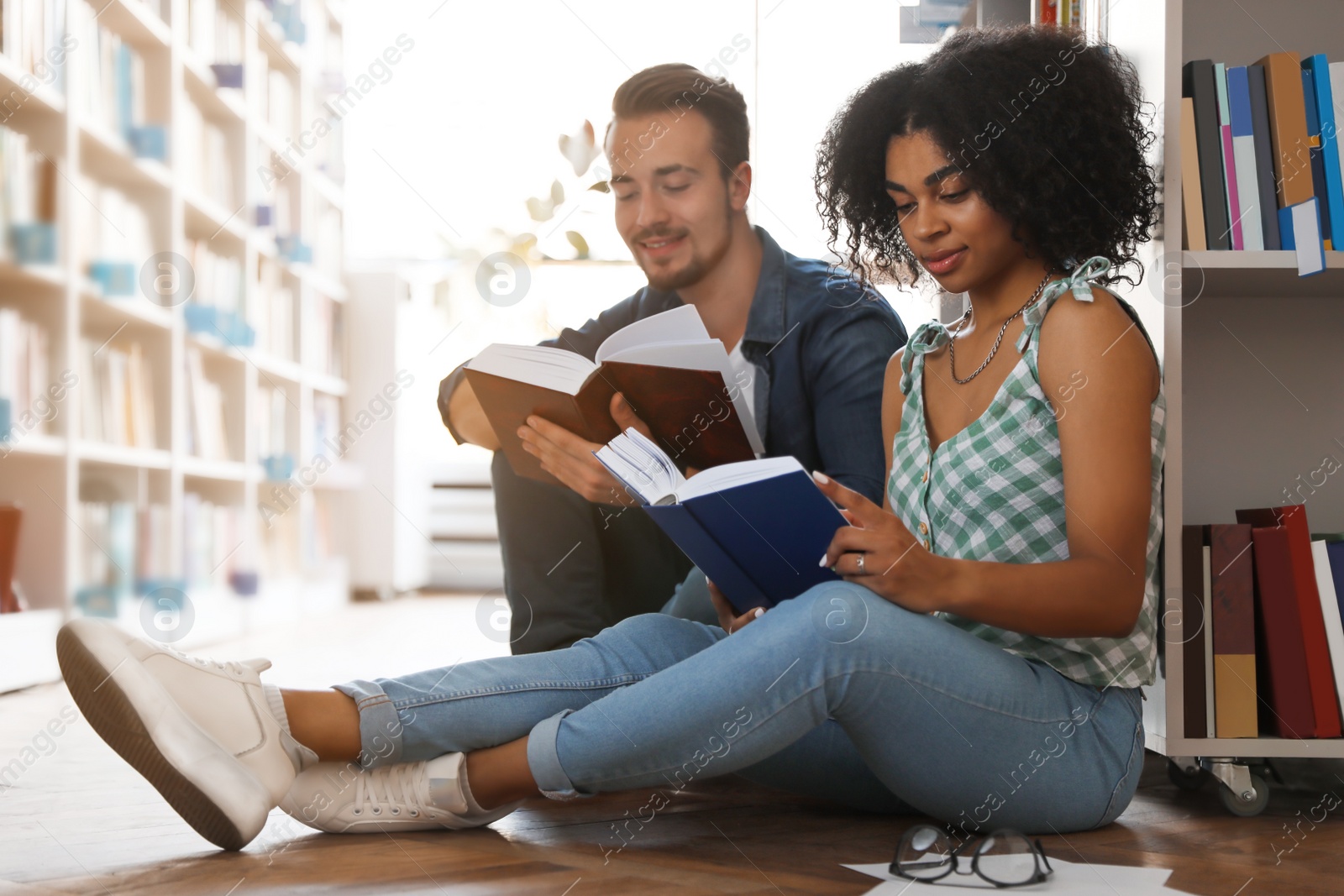 Photo of Young people with books on floor in library