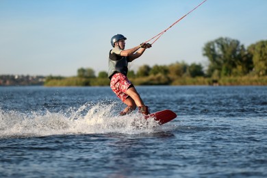 Photo of Teenage boy wakeboarding on river. Extreme water sport