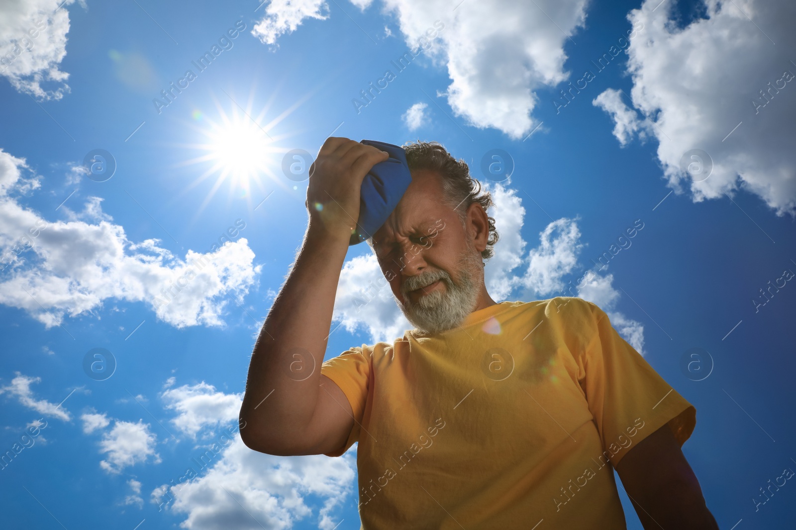 Photo of Senior man with cold pack suffering from heat stroke outdoors, low angle view