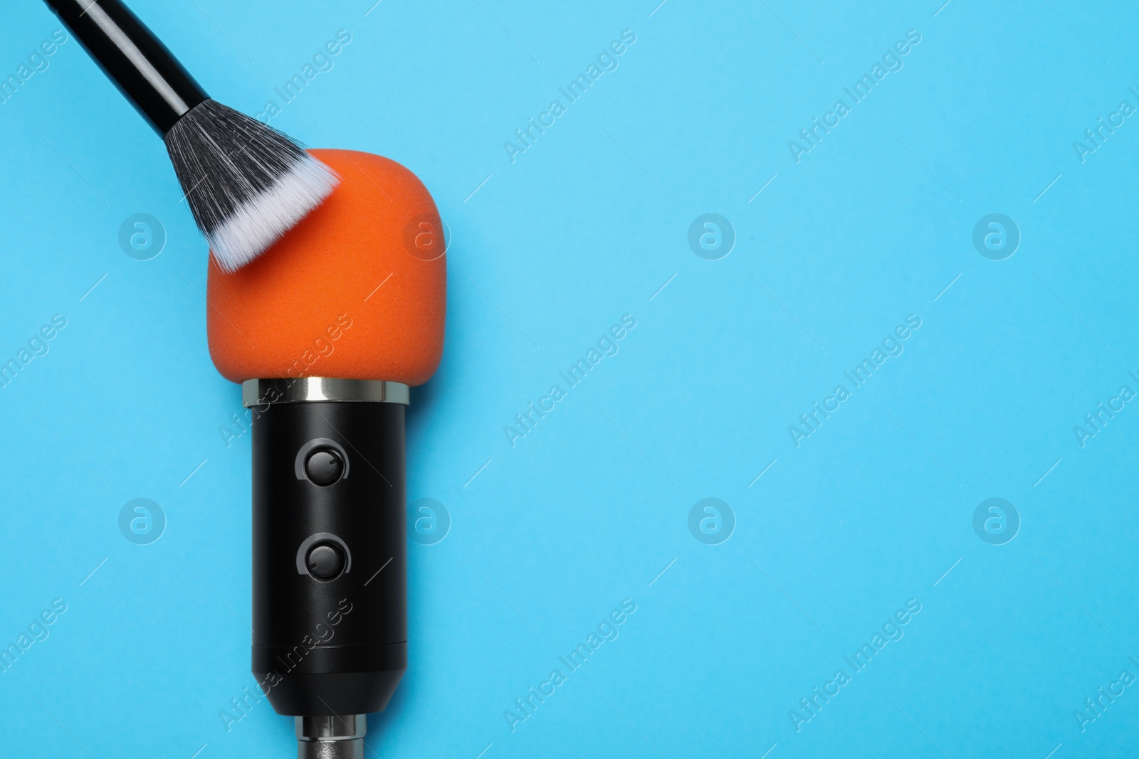 Photo of Making ASMR sounds with microphone and brush on light blue background, flat lay. Space for text
