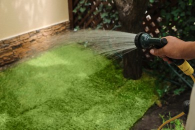 Photo of Man watering unrolled grass sods at backyard, closeup