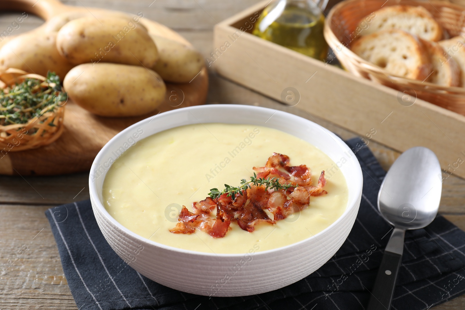 Photo of Tasty potato soup with bacon and rosemary in bowl served on wooden table