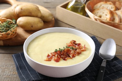 Photo of Tasty potato soup with bacon and rosemary in bowl served on wooden table