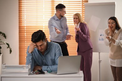 Photo of Coworkers bullying their colleague at workplace in office