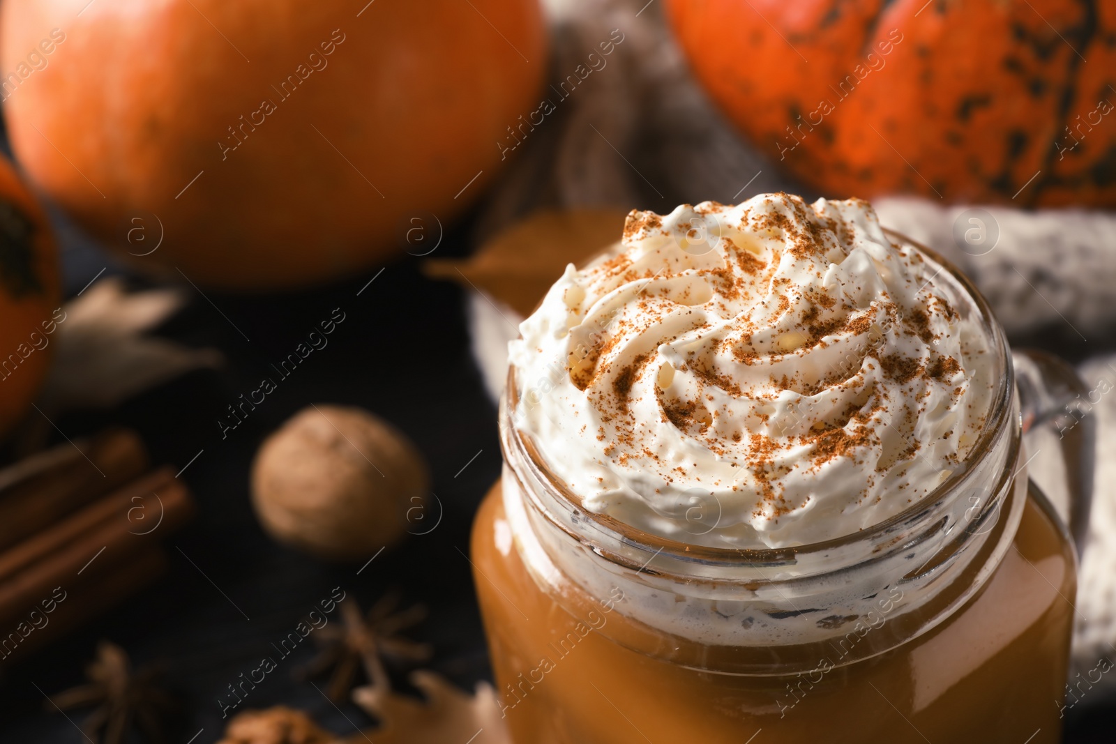 Photo of Mason jar with tasty pumpkin spice latte on table, closeup