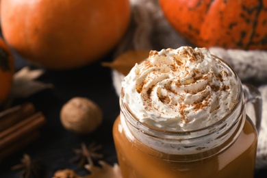 Photo of Mason jar with tasty pumpkin spice latte on table, closeup