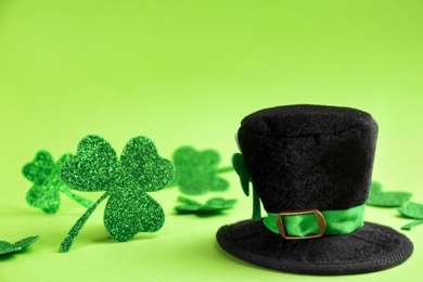 Photo of Leprechaun's hat and decorative clover leaves on green background. St. Patrick's day celebration