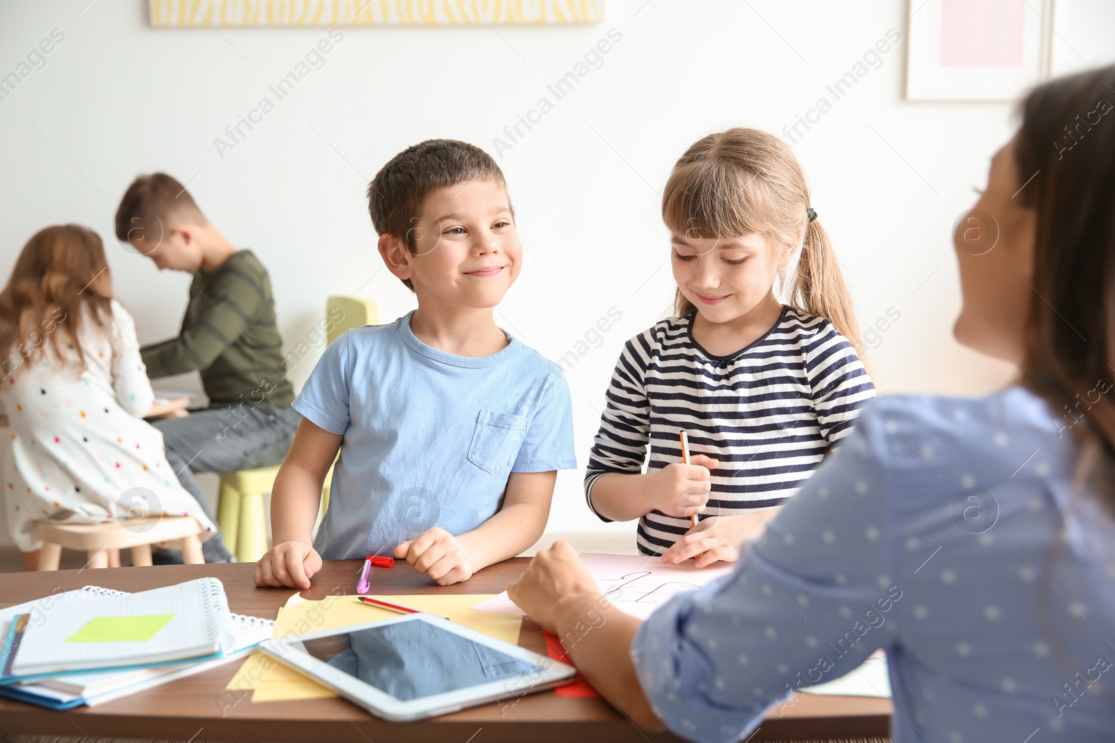 Photo of Cute little children with teacher in classroom at school