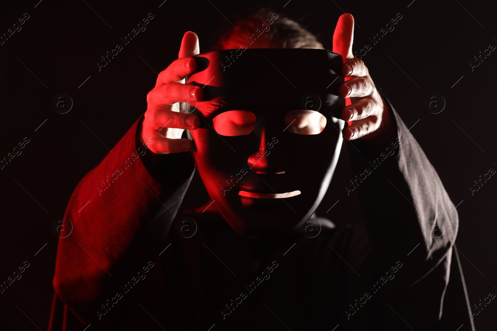 Photo of Theatrical performance. Man with plastic mask on dark background