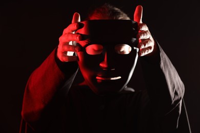 Photo of Theatrical performance. Man with plastic mask on dark background