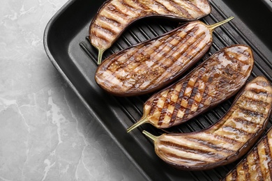 Delicious grilled eggplant halves in pan on grey table, top view