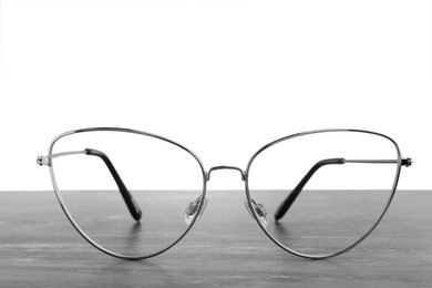 Photo of Stylish glasses with metal frame on table against white background