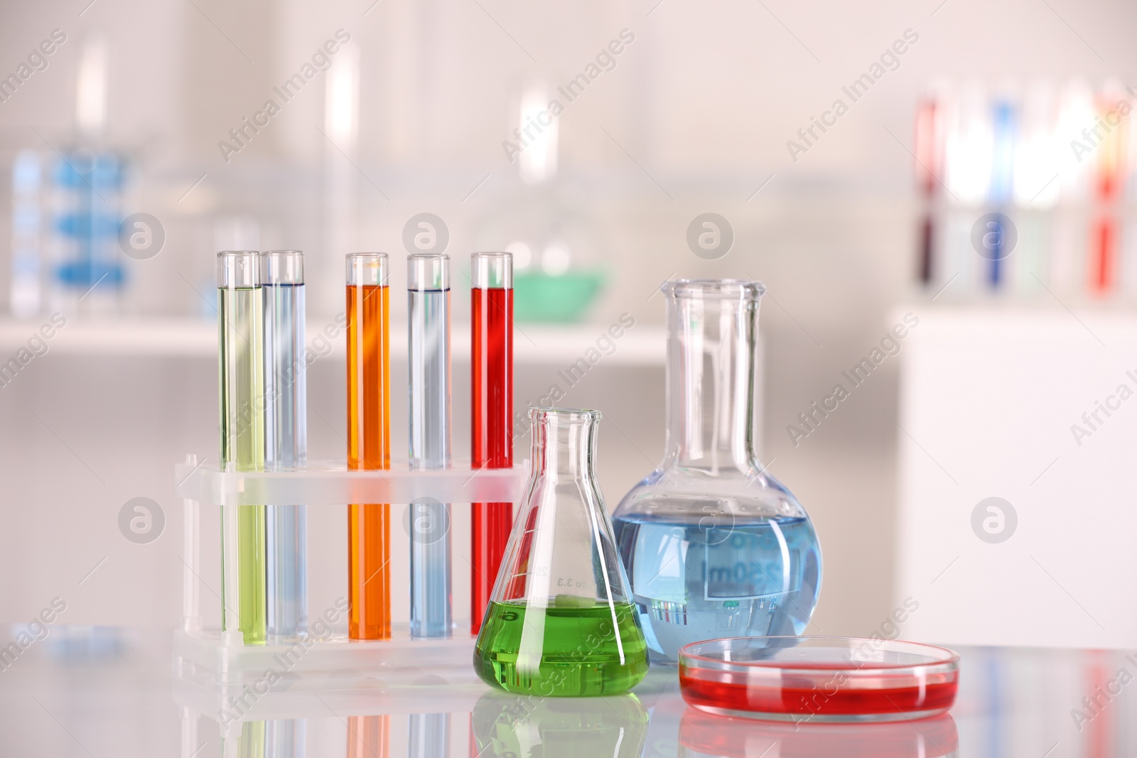 Photo of Laboratory analysis. Different glassware with liquids on white table against blurred background. Space for text