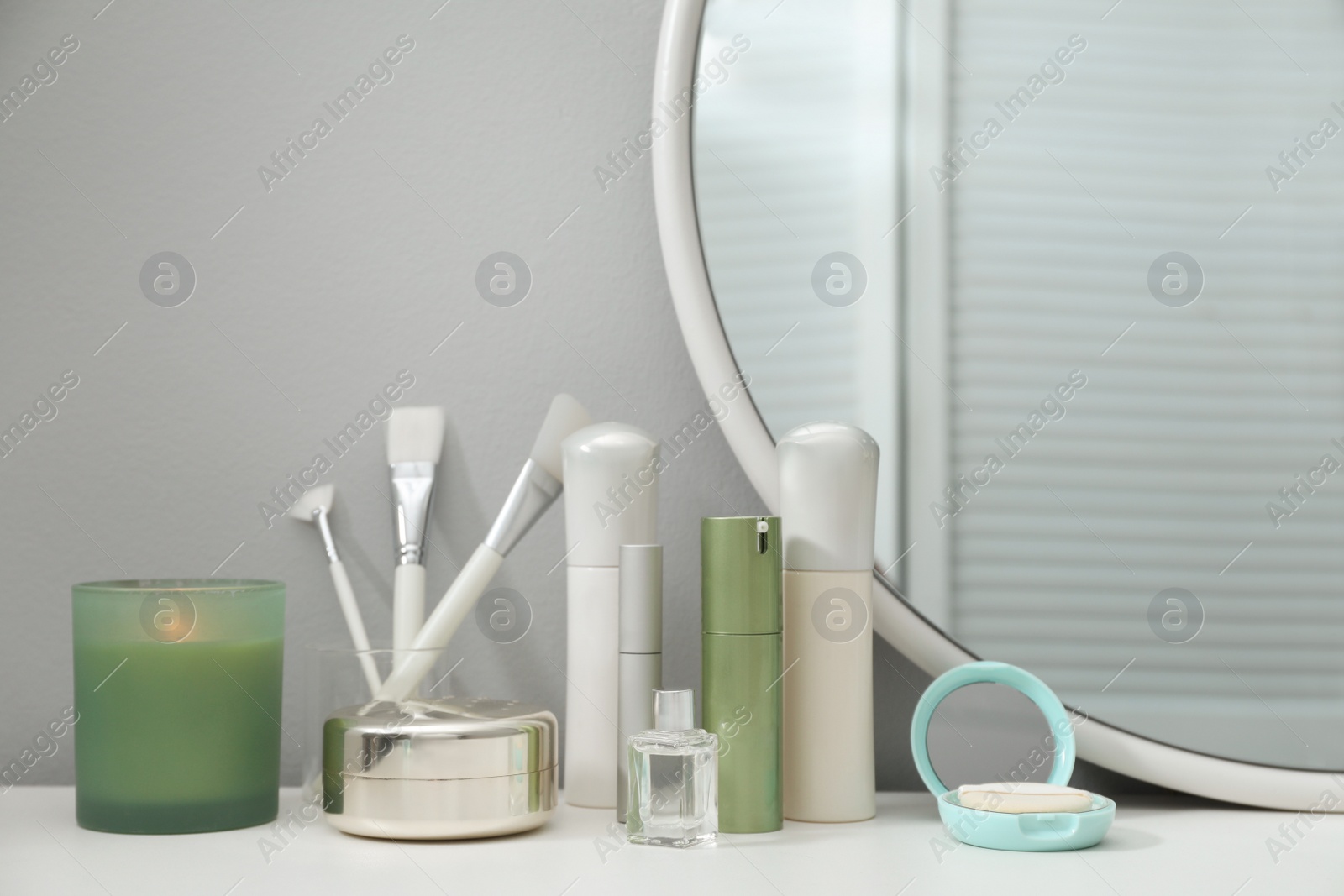 Photo of Stylish round mirror on dressing table with cosmetic products